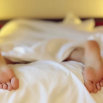 stopy śpiącej osoby wystające spod kołdry o poranku